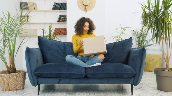 Excited Young Woman Unpacking Huge Carton Box Looking Inside