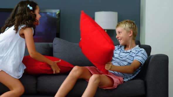 Siblings having pillow fight in living room