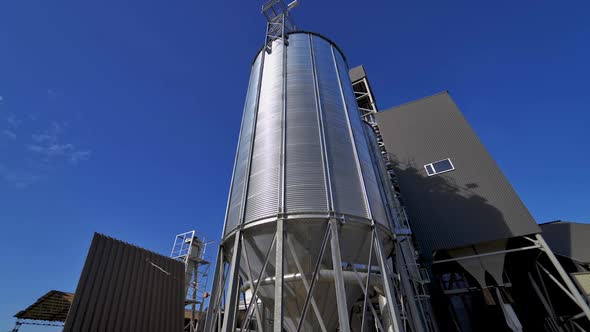 Modern silos on blue sky background. Large silver grain elevator outdoors.