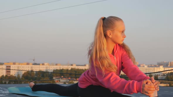 Beautiful Young Girl Teenager in a Pink Blouse Is Engaged in Gymnastics on the Roof
