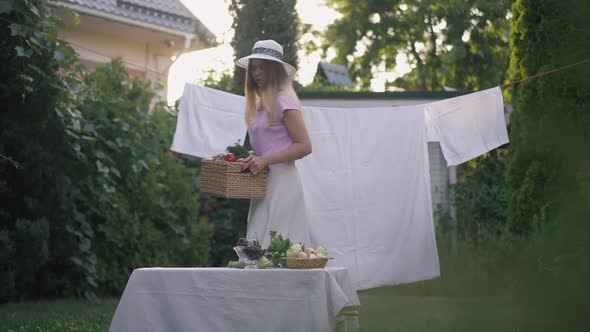 Wide Shot Confident Caucasian Young Woman Walking with Vegetable Basket to Table on Backyard