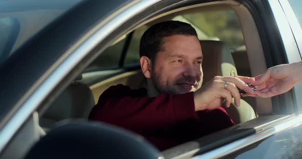 Close Up of Woman Hand Giving Keys to Young Man That Sitting in New Car