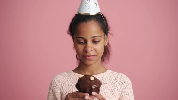 Positive African little girl eating holiday cupcake