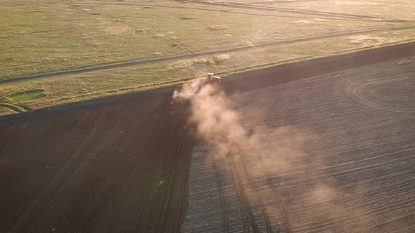 Aerial View Modern Red Tractor on the Agricultural Field on Sunset Time. Tractor Plowing Land and