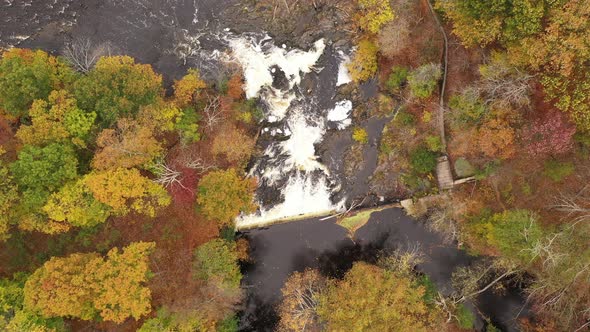 A top down shot directly above a waterfall, surrounded by colorful fall foliage in upstate NY. The c