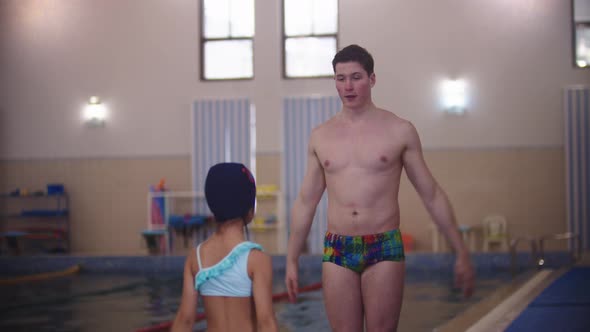 Swimming Instructor Warming Up Their Shoulders with a Little Girl By the Pool
