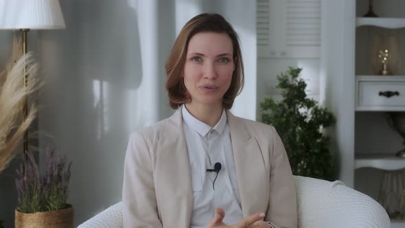 Young beautiful girl, blogger, vlogger, influencer, sitting at home, talking, looking at the camera