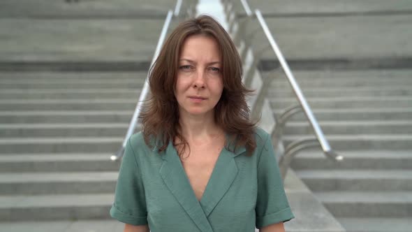 Portrait of a Middle-aged Brunette in a Green Dress. She Goes To the Camera Against the Background