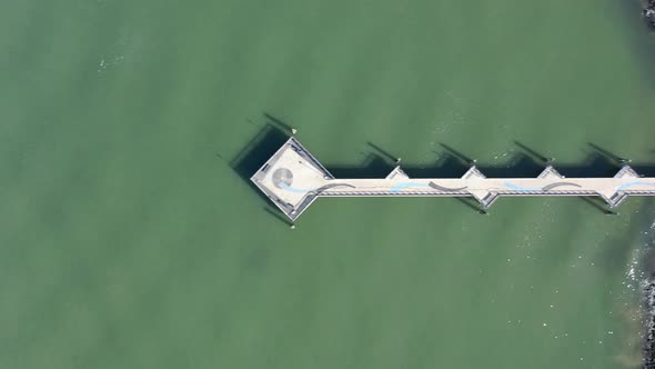 A top down shot over a pier in the green water in Red Hook Channel on a sunny morning. The camera tr