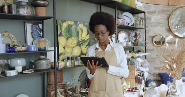 African American Woman Working on Tablet pc in Beautiful Handmade Souvenirs Shop 