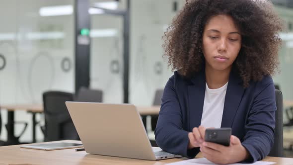 African Businesswoman with Laptop Using Smartphone 