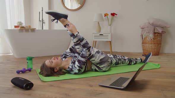 Charming Sporty Fitness Woman Practicing Reclining Hamstring Stretch in Domestic Room