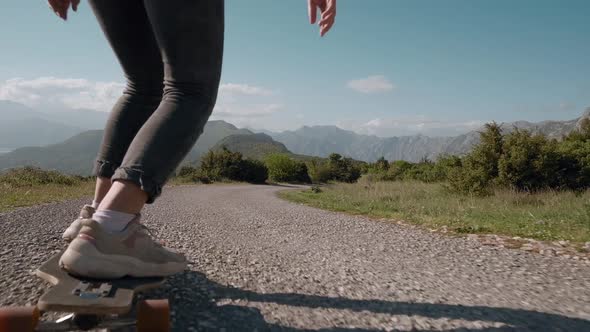 Close up of woman feet longboarding on mountain background riding skateboard