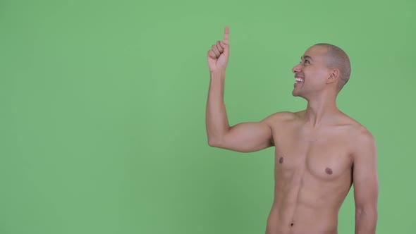 Happy Bald Multi Ethnic Shirtless Man Pointing Up and Looking Surprised