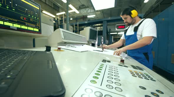 Engineer, Worker at a Factory Facility. Operation Board and a Male Worker Taking Notes Near It