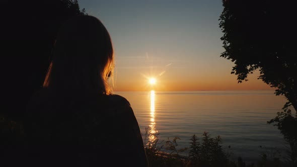 Woman Tourist Admires the Sunset Over the Sea in the Tropics