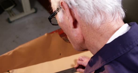 Shoemaker marking a piece of leather with pencil