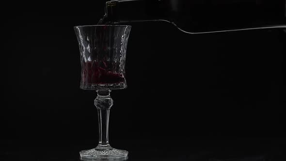 Rose Wine. Red Wine Pour in Wine Glass Over Black Background. Slow Motion