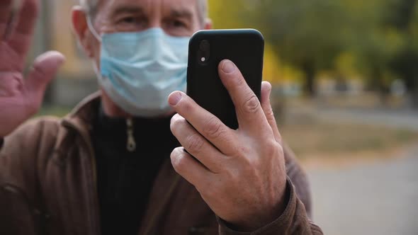 Senior Man Wearing a Medicinal Mask Talking on Video Chat with Their Children.