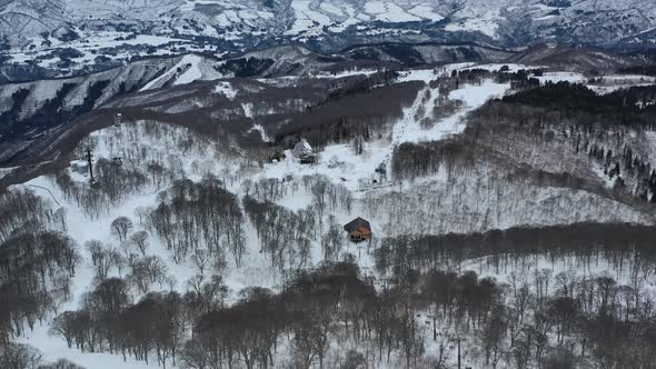 small cabin in the mountain hills during winter covered in snow at nozawa onsen japan, aerial