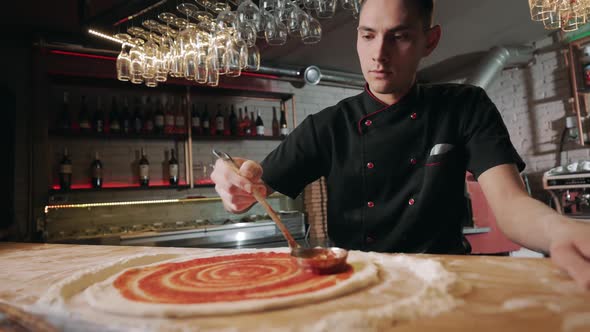 Man Spreading Sauce on Pizza Dough