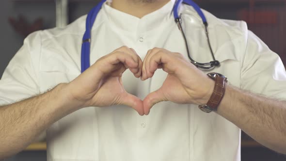 Close up of doctor with stethoscope showing heart gesture with his hands