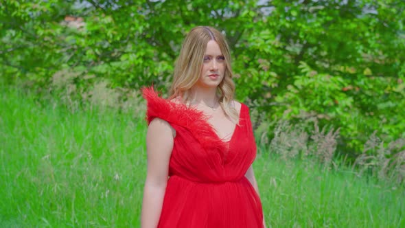 Beautiful Girl with Red Dress Walks Among Green Nature