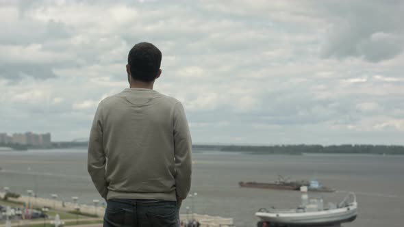 A Young Businessman Is Standing By the River, Looking Forward and Thinking.