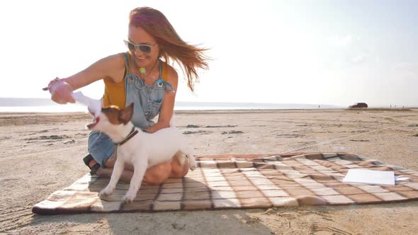 Young Stylish Hipster Playing Dog Puppy Jack Russell on the Beach Slow Motion