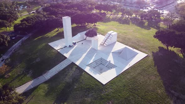 Aerial forward high angle drone view of Wolfson Park's white monuments, trees and grass on a sunny d