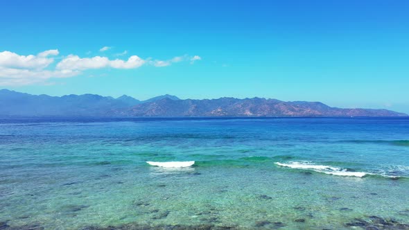 Tropical overhead travel shot of a sandy white paradise beach and blue water background in colorful 