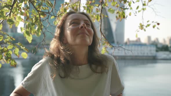 Portrait of a Brunette on the City Embankment Against the Background of Modern Buildings