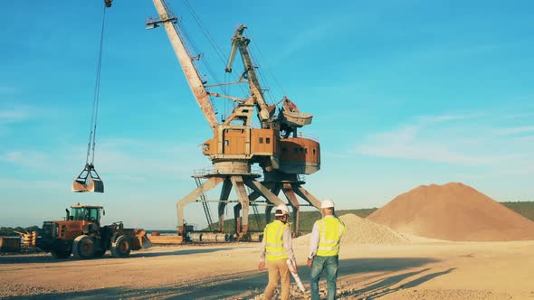 Male Specialists Are Walking Along the Quarry Site with Machines