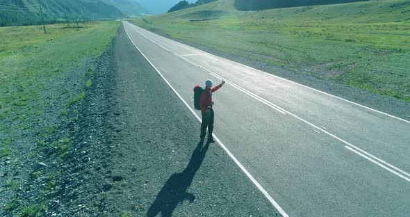 Flight Over Hitchhiker Tourist Walking on Asphalt Road