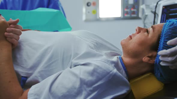 Man comforting pregnant woman during labor in operation theater at hospital 