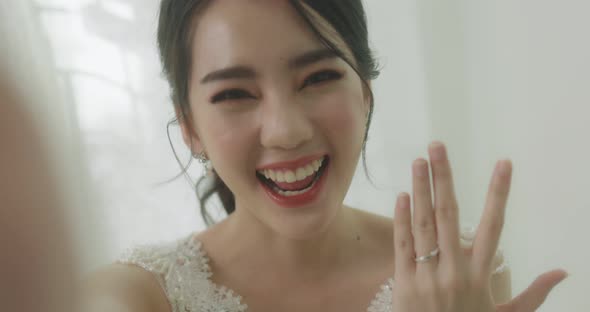 Happy Beautiful Asian Bride Shows Wedding On Her Ring Finger To Her Friend By Smartphone Video Call.