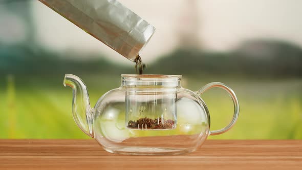 Putting Dry Tea Leaves Into Teapot on a Wooden Table