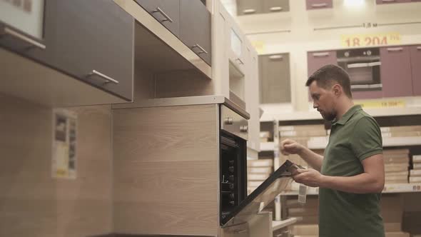 Buyer is Inspecting Showpiece of Oven in Kitchen in a Furniture Store