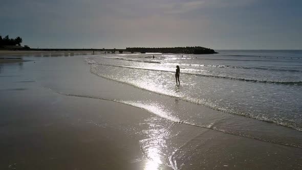 Lady Silhouette Goes Along Sea Edge Under Sunlight