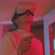 Young woman wearing vr goggles and holding handle device turns around with neon light in the back - VideoHive Item for Sale