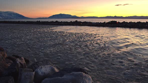 Sunset glow in lake with ice floating in water as car drives on pier