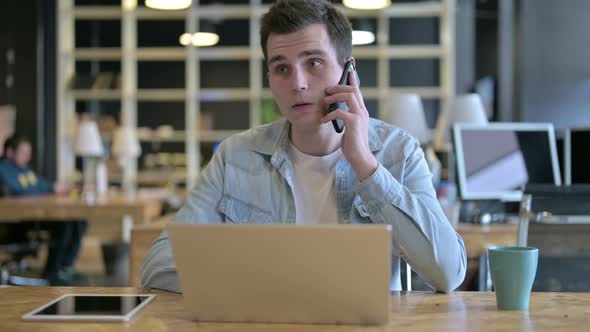 Attractive Young Designer Talking on Smartphone in Office
