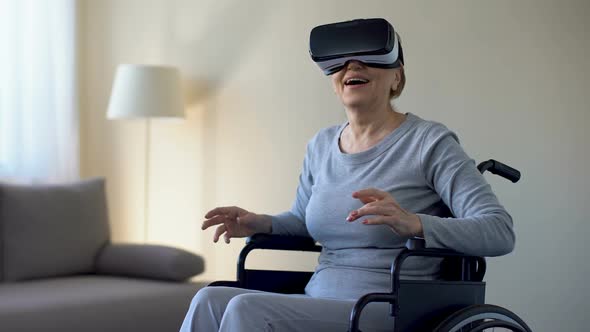 Impressed Grandmother in Wheelchair Wearing Goggles, Playing VR Game, Device