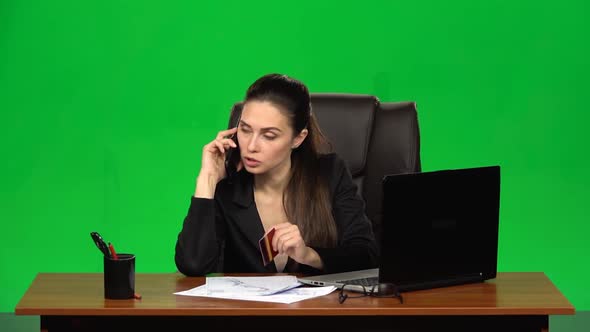 Woman at the Workplace Takes a Credit Card and Call on the Phone. Green Screen. Studio. Slow Motion