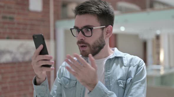 Portrait of Young Male Designer Shocked Using Smartphone