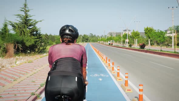 Female pro cyclist pedaling on road bike