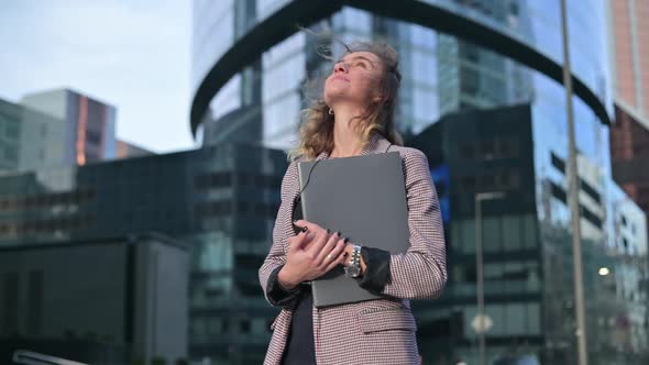 office worker stands with a folder and documents in her hand and smilingly looks