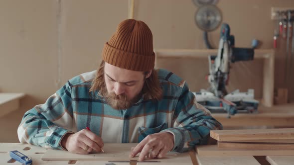 Male Caucasian Carpenter Drawing on Wooden Board
