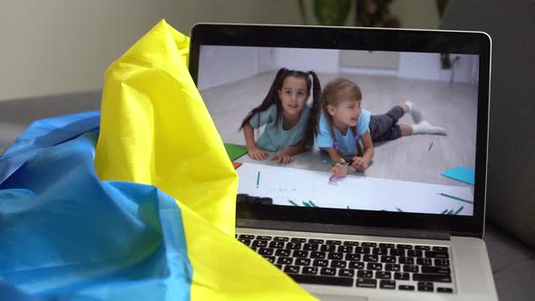 Laptop with Video Cbaby Toddler Near the Flag of Ukraine