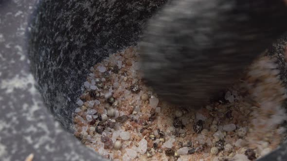 Closeup of Pestle Crushing and Mixing Salt and Spices in the Grey Stone Mortar